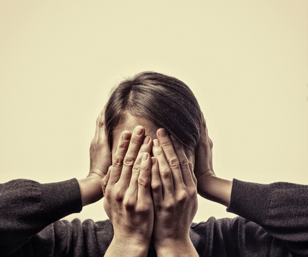 Concept of fear, domestic violence. Woman's hands covers her face and ears.の写真素材
