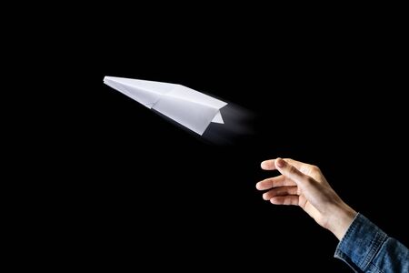 Image of a hand is throwing  white paper plane on black background.の写真素材