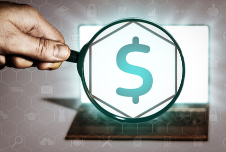 Hand holds the magnifying glass in front of an open notebook. Among the many icons, attention is focused on the money icon. Financial operations, banking, lending, etc.の写真素材