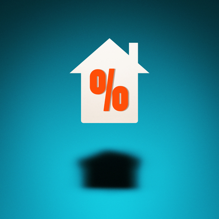 Home on credit or mortgage. An icon of a house hovers in the air, casting a shadow on blue background. The symbol "percent" is inscribed in the silhouette of the house.の写真素材