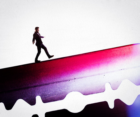 The concept of risk. A man in a business suit is walking along the razor's blade.の写真素材