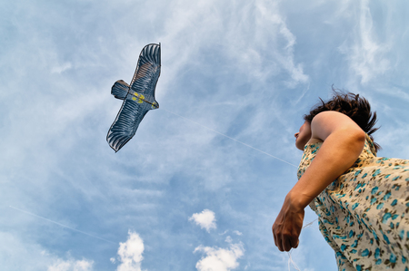 Happy young woman running with a kite on a beach at sunset in summer.の写真素材