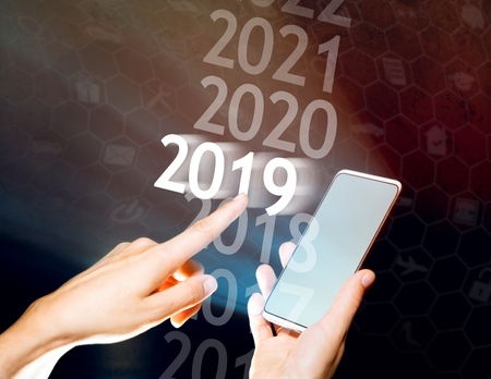Hand select 2019 on her smartphone. New year in high tech.