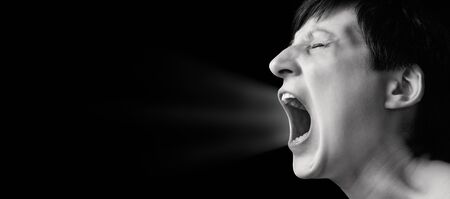 Concept of anger. Portrait of a screaming woman on isolated background with free space. Black and white image.の写真素材