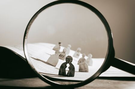 Business recruitment or hiring photo concept. Looking for talent. Icons of candidates are standing on open newspaper under magnifier.の写真素材