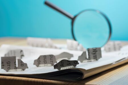 Open newspaper with paper cars. Concept of car rental, search, purchase and cargo transportation.の写真素材