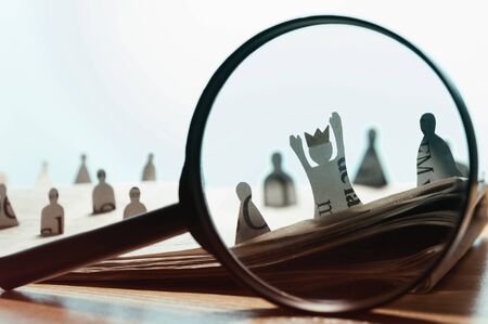 Business recruitment or hiring photo concept. Looking for talent. Icons of candidates are standing on open newspaper under magnifier.の写真素材