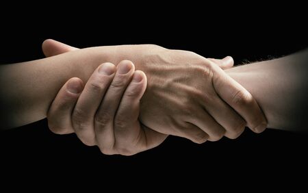 Concept of rescue. Image of the hands of two people during the rescue. On black background.
