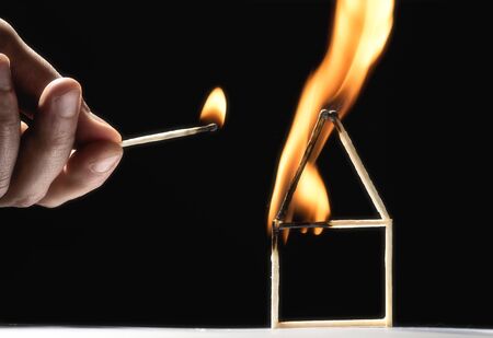 Human sets fire to house from matches. On blackの写真素材