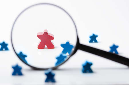 A toy red wooden figure of human under magnifying lens. Business recruitment, talent management.の写真素材