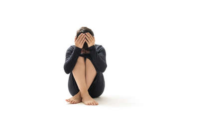 Woman covers her face with her hands while sitting on the floor. Concept of fear, shame, domestic...