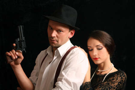 Portrait of the man in a hat with a pistol and the beautiful woman. In style of a retro.の写真素材