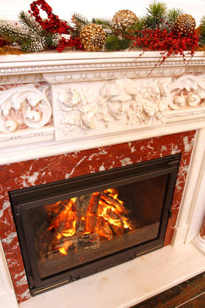 Christmas ornaments on a marble fireplace. In a fireplace fire burns.の写真素材