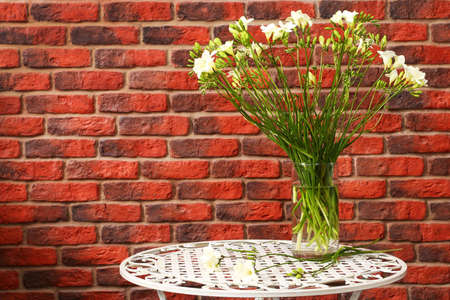 Flowers on a metal shod table against a wall from a red brick? の写真素材