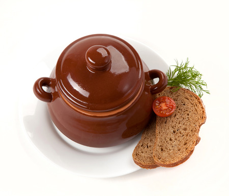 roast with greens and tomato in a brown clay potの写真素材