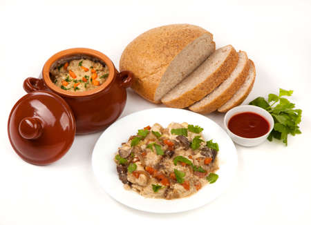 roast with greens, sauce, bread and tomato in a brown clay potの写真素材