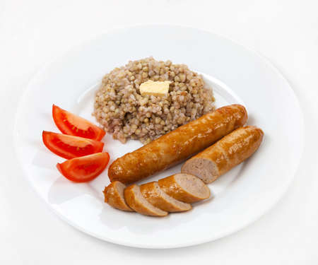 sausages a grill with porridge and tomatoes on a white plateの写真素材