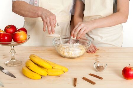 the grandmother and the granddaughter fill ingredients in a bowl on a white backgroundの写真素材