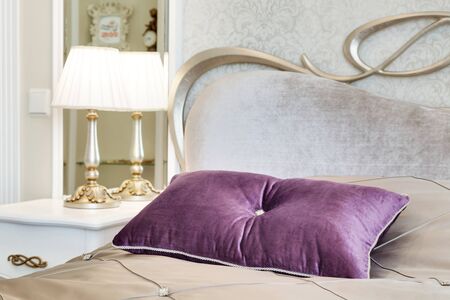 little table with a lamp and a bed with pillows in a modern bedroomの写真素材