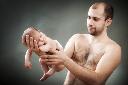 the father holds on hands of the newborn childの写真素材