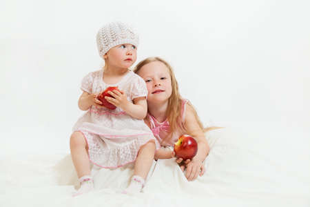 two little girls sit on the isolated backgroundの写真素材