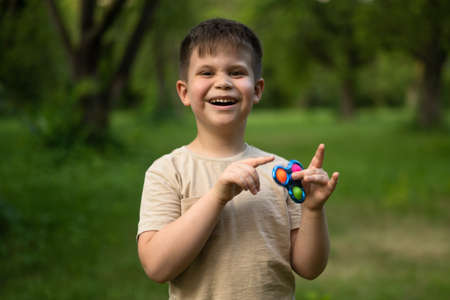 Happy Boy on a Walk in the Suburb. A Cute Boy Spins Spinner. Summer Day With Son. High quality photoの写真素材