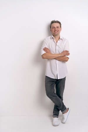 Full length portrait of young handsome man in white shirt and eye glasses smiling, with a happy and...