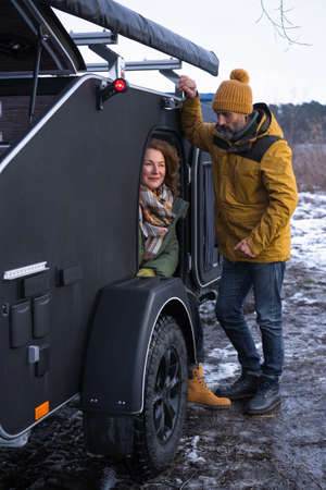 Mature couple rest in camper traveling across country. Middle aged couple rest in camper smile good mood at winter vacation in the wild. woman look with love on her husband. Journey concept.の写真素材