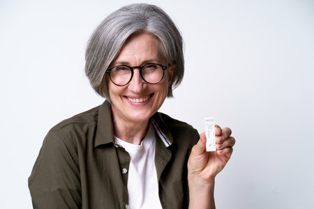 Happy gray haired mature woman showing  self test, excited of negative result wearing casual green...