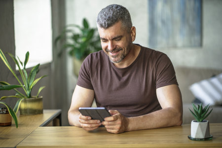 Gray haired freelancer working remotely at home using tablet. Portrait of smiling middle aged man...