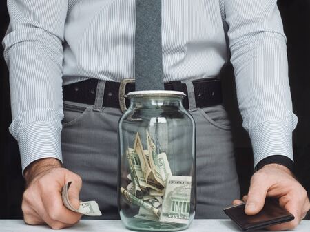 transparent glass jar that is used by a young man as a piggy bankの写真素材