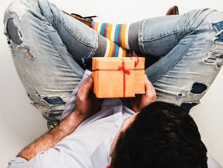 Handsome man in funny socks and stylish shoes with a gift for his loved oneの写真素材
