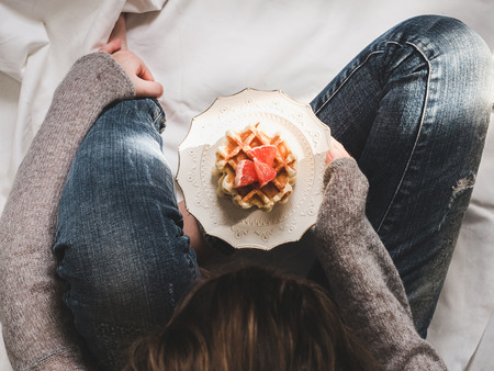 Young woman sitting on a plaid with a plate of fresh cookies, decorated with slices of red grapefruitの写真素材
