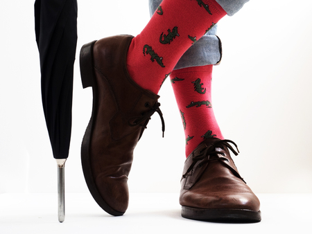 Men's legs in bright, funny socks and stylish shoes near the umbrellaの写真素材