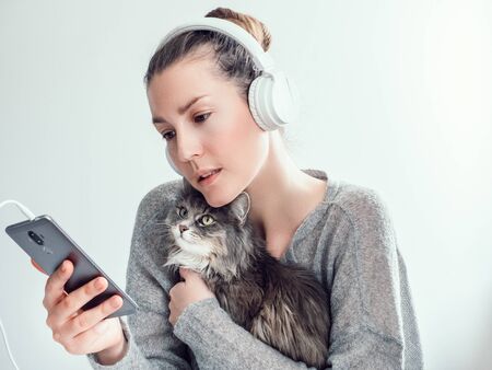 Stylish woman in headphones and with her kittenの写真素材
