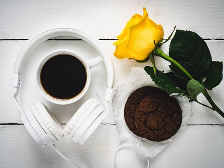 Fragrant coffee, fresh cookies, yellow rose and headphones on a white table. The view from the top. Style, fashion, beautyの写真素材