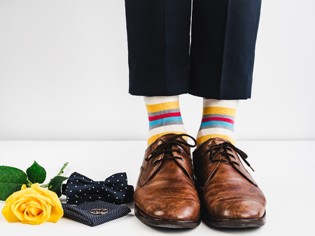 Wedding rings, yellow rose, bow tie, handkerchief, bright, funny socks and male legs in stylish brown shoes on a white background. Wedding preparationsの写真素材