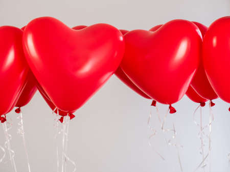 Red balloons in the shape of a heart filled with helium, on a white background. Festive eventの写真素材