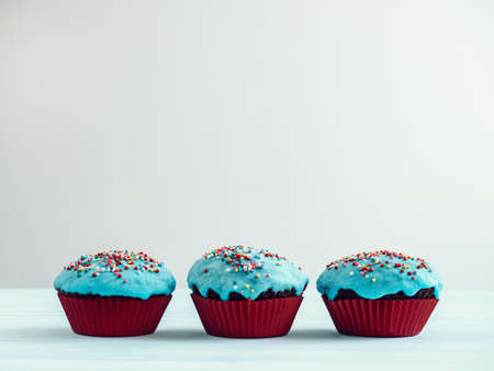 Festive, fragrant cupcakes, covered with turquoise glaze and bright decoration for baking on a white backgroundの写真素材