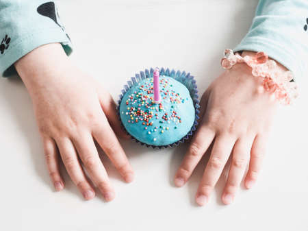 Festive, fragrant cupcake with a candle, covered with blue glaze and a bright decoration for baking,...
