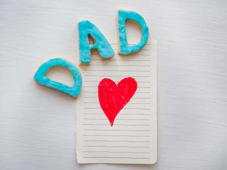 Postcard with painted red heart and word DAD on white, isolated background. Congratulation to the father. Preparation for Father's Dayの写真素材