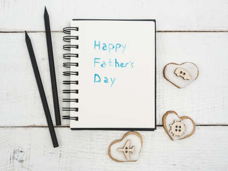 Glazed heart shaped cookies, sketchbook with handwritten congratulation on Father's day on a beautiful, white table. Top view. Happy family conceptの写真素材
