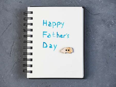 Notepad with handwritten greeting on Father's day on a beautiful, grey table. View from the top. Concept of a happy familyの写真素材