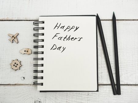 Glazed cookies and sketchbook with handwritten congratulation on Father's day on a beautiful, white table. Top view. Happy family conceptの写真素材