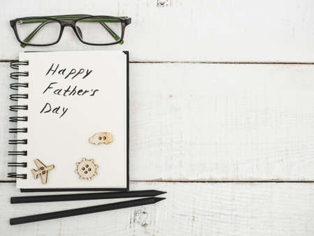 Glazed cookies and sketchbook with handwritten congratulation on Father's day on a beautiful, white table. Top view. Happy family conceptの写真素材