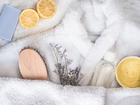 White bathrobe, aroma-oil, cream-scrub, shampoo, piece of lavender soap, slice of lemon and a...