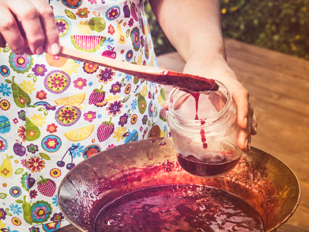 Old, copper pan, wooden spoon and plum jam
