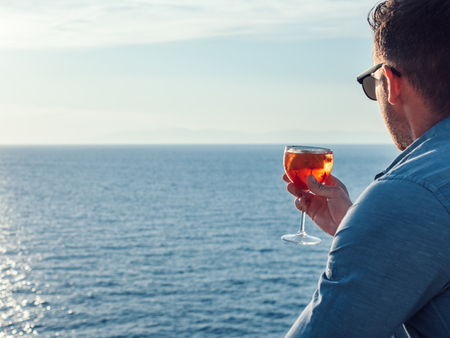 Attractive, stylish man in sunglasses, holding a glass of beautiful pink cocktailの写真素材