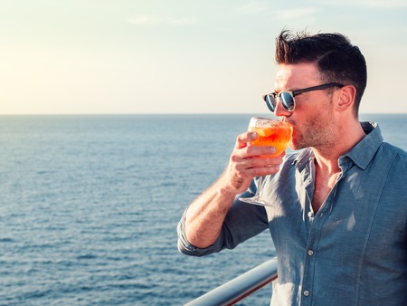 Attractive, stylish man in sunglasses, holding a glass of beautiful pink cocktailの写真素材