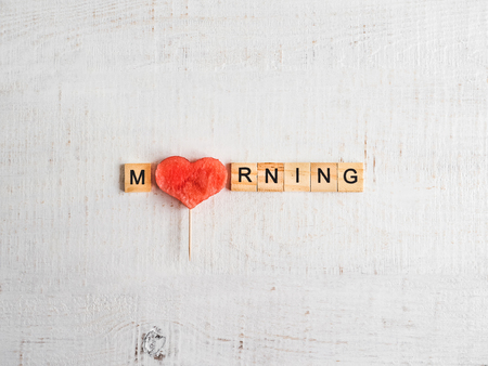 Wooden letters in the form of the word MORNING, a slice of watermelon and a shabby surface of white color. Top view, close-up, isolated. Preparation for the holiday. Congratulations for loved onesの写真素材